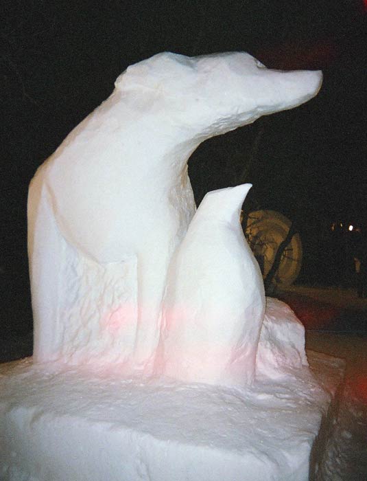 Snöskulptur av pingvin och hund